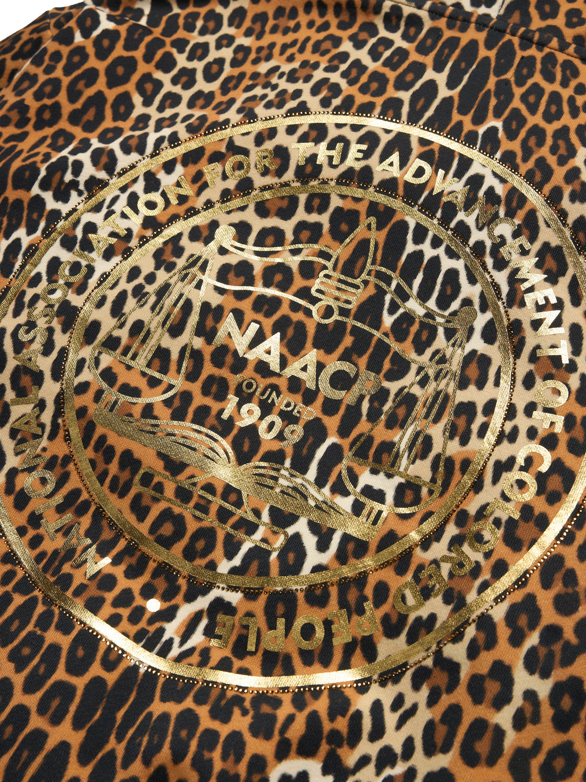 Close-up of a leopard print fabric with a large metallic gold circular logo printed in the center. The pattern features black and brown spots on a tan background, and the logo includes the text 'NAACP' and 'LONDON 1908'.