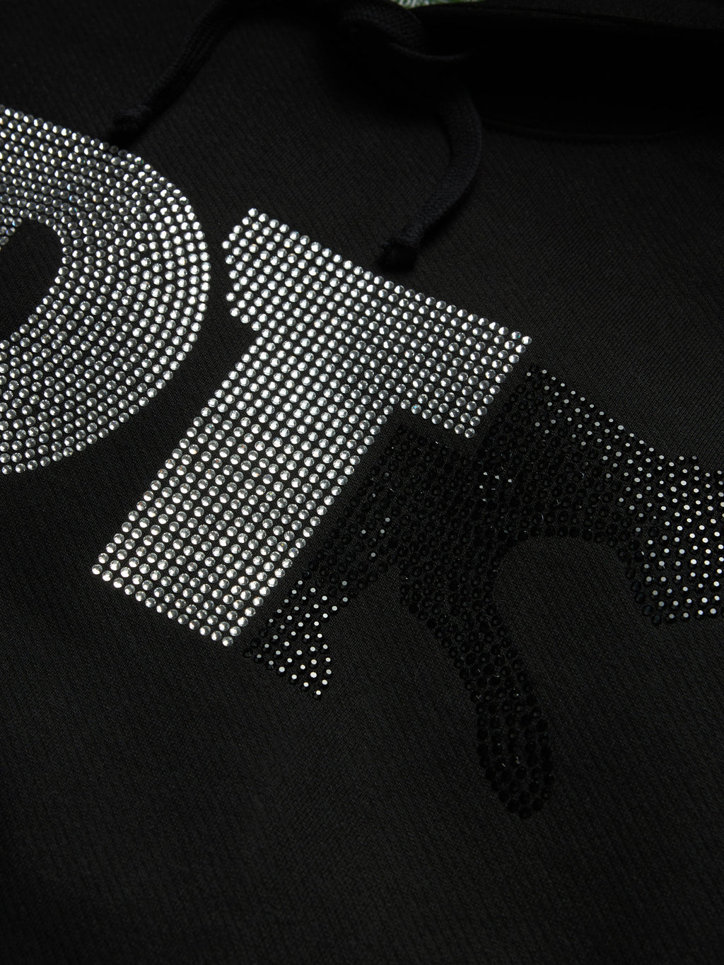 Close-up of a black Denim Tears hoodie featuring a large, stylized letter 'T' embellished with silver rhinestones, with a matching black rhinestone silhouette of a bear on the front.